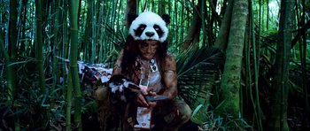 Movie still from “Tropic Thunder” (2008), directed by Ben Stiller – A person with a panda bear mask on holding something; Medium shot, Overhead angle