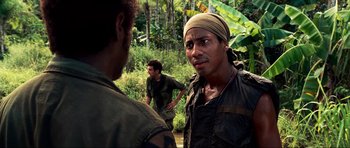 Movie still from “Tropic Thunder” (2008), directed by Ben Stiller – A group of men standing next to each other in the woods; Close Up shot, Over the shoulder angle