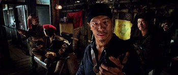 Movie still from “Tropic Thunder” (2008), directed by Ben Stiller – A man in a black shirt and a black hat holding a cell phone; Close Up shot, Low angle