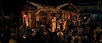 Movie still from “Tropic Thunder” (2008), directed by Ben Stiller – A group of people on a stage performing a show; Wide shot, Over the shoulder angle