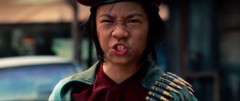 Movie still from “Tropic Thunder” (2008), directed by Ben Stiller – A person with a hat on and a bunch of bullets in their mouth; Close Up shot, Low angle