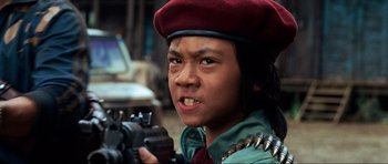 Movie still from “Tropic Thunder” (2008), directed by Ben Stiller – A person with a gun wearing a red hat; Close Up shot, Low angle