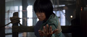 Movie still from “Tropic Thunder” (2008), directed by Ben Stiller – A woman is standing in a room with her hands in the air; Close Up shot, Low angle