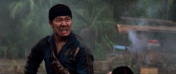 Movie still from “Tropic Thunder” (2008), directed by Ben Stiller – A man with a black headband and a black jacket is looking angry; Close Up shot, Over the shoulder angle