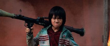 Movie still from “Tropic Thunder” (2008), directed by Ben Stiller – A young boy holding a gun in his hands; Medium shot, Low angle