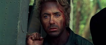 Movie still from “Tropic Thunder” (2008), directed by Ben Stiller – A person with a scar on his face; Close Up shot, Over the shoulder angle