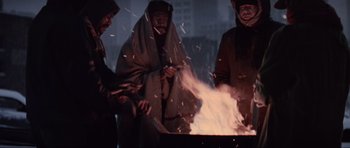 Movie still from “True Romance” (1993), directed by Tony Scott – A group of people standing around a fire pit; Medium shot, High angle