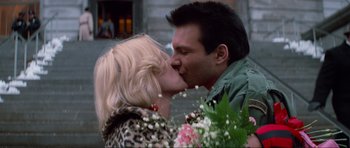 Movie still from “True Romance” (1993), directed by Tony Scott – A man and a woman kissing in front of a bunch of flowers; Close Up shot, Low angle