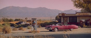Movie still from “True Romance” (1993), directed by Tony Scott – An old car parked next to a gas station; Extreme Wide shot, Low angle