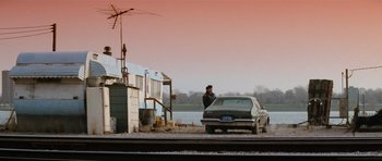Movie still from “True Romance” (1993), directed by Tony Scott – A man standing next to a car on the side of the road; Extreme Wide shot, Low angle