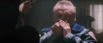 Movie still from “True Romance” (1993), directed by Tony Scott – An older man is holding his hands to his face; Close Up shot, Low angle