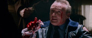 Movie still from “True Romance” (1993), directed by Tony Scott – A man with blood on his face holding something in his hand; Close Up shot, High angle