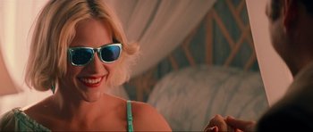 Movie still from “True Romance” (1993), directed by Tony Scott – A woman wearing sunglasses and smiling for the camera; Close Up shot, Over the shoulder angle