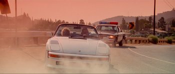 Movie still from “True Romance” (1993), directed by Tony Scott – A couple of police cars driving down a street; Wide shot, Low angle