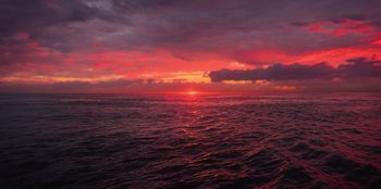 Movie still from “True Spirit” (2023), directed by Sarah Spillane – The sun is setting over the ocean as seen from a boat; Extreme Wide shot, High angle