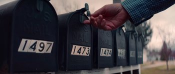 A person is putting a number on a mail box