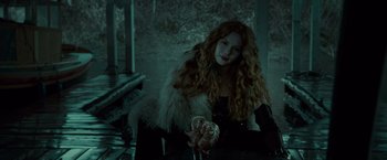 Movie still from “Twilight” (2008), directed by Catherine Hardwicke – A woman with long red curly hair sitting at a table; Medium shot, Over the shoulder angle