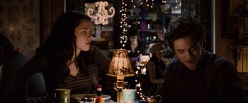 Movie still from “Twilight” (2008), directed by Catherine Hardwicke – Two people are sitting at a table with a lamp; Medium shot, Over the shoulder angle