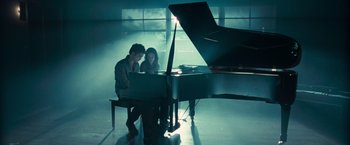 Movie still from “Twilight” (2008), directed by Catherine Hardwicke – A man and a woman sitting at a piano in a room; Wide shot, High angle