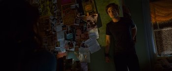Movie still from “Twilight” (2008), directed by Catherine Hardwicke – A man standing in front of a wall covered with papers; Medium shot, High angle