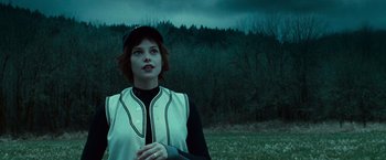 Movie still from “Twilight” (2008), directed by Catherine Hardwicke – A woman standing in front of a field with trees in the background; Close Up shot, Low angle