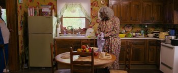 Movie still from “Tyler Perry's A Madea Homecoming” (2022), directed by Tyler Perry – An older woman in a floral dress in a kitchen; Wide shot, High angle