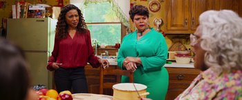 Movie still from “Tyler Perry's A Madea Homecoming” (2022), directed by Tyler Perry – Two women standing in a kitchen next to a pot; Medium shot, Over the shoulder angle