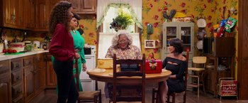 Movie still from “Tyler Perry's A Madea Homecoming” (2022), directed by Tyler Perry – A group of people sitting at a table in a room; Wide shot, High angle