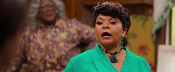 Movie still from “Tyler Perry's A Madea Homecoming” (2022), directed by Tyler Perry – An older woman wearing a green dress and a green necklace; Close Up shot, Over the shoulder angle