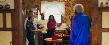 Movie still from “Tyler Perry's A Madea Homecoming” (2022), directed by Tyler Perry – A group of people standing around a table in a room; Wide shot, Over the shoulder angle