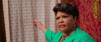 Movie still from “Tyler Perry's A Madea Homecoming” (2022), directed by Tyler Perry – An older woman in a green shirt pointing to a curtain; Close Up shot, Over the shoulder angle
