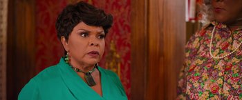 Movie still from “Tyler Perry's A Madea Homecoming” (2022), directed by Tyler Perry – A woman in a green dress and a green necklace; Close Up shot, Over the shoulder angle
