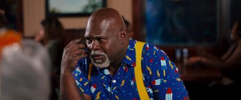 Movie still from “Tyler Perry's A Madea Homecoming” (2022), directed by Tyler Perry – An older black man wearing a colorful shirt and yellow suspenders; Close Up shot, Low angle