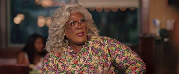 Movie still from “Tyler Perry's A Madea Homecoming” (2022), directed by Tyler Perry – A woman with blonde hair wearing a floral shirt and glasses; Close Up shot, High angle