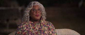 Movie still from “Tyler Perry's A Madea Homecoming” (2022), directed by Tyler Perry – A woman in a floral print shirt and glasses; Close Up shot, Over the shoulder angle