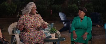 Movie still from “Tyler Perry's A Madea Homecoming” (2022), directed by Tyler Perry – Two women sitting at an outdoor table talking to each other; Medium shot, Over the shoulder angle