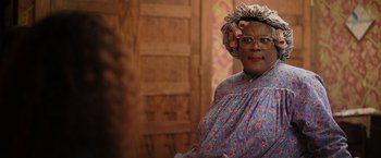 Movie still from “Tyler Perry's A Madea Homecoming” (2022), directed by Tyler Perry – An older woman in a blue dress is posing for a picture; Close Up shot, Over the shoulder angle