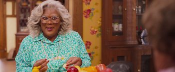 Movie still from “Tyler Perry's A Madea Homecoming” (2022), directed by Tyler Perry – A woman sitting at a table with a plate of fruit; Close Up shot, High angle
