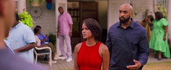 Movie still from “Tyler Perry's A Madea Homecoming” (2022), directed by Tyler Perry – A woman in a red dress standing in front of two men; Medium shot, Over the shoulder angle