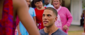 Movie still from “Tyler Perry's A Madea Homecoming” (2022), directed by Tyler Perry – A group of people standing around a man with his eyes closed; Close Up shot, Over the shoulder angle