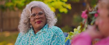 Movie still from “Tyler Perry's A Madea Homecoming” (2022), directed by Tyler Perry – A person wearing glasses and a floral shirt; Close Up shot, Over the shoulder angle