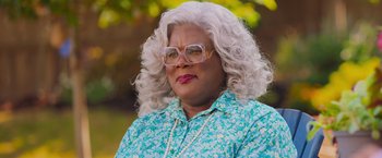 Movie still from “Tyler Perry's A Madea Homecoming” (2022), directed by Tyler Perry – A woman with white curly hair wearing glasses and a floral shirt; Close Up shot, Over the shoulder angle