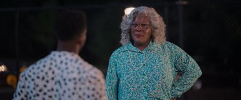 Movie still from “Tyler Perry's A Madea Homecoming” (2022), directed by Tyler Perry – A woman in a floral shirt and glasses; Medium shot, Over the shoulder angle