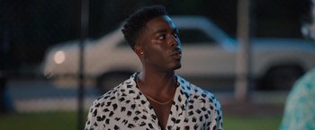 Movie still from “Tyler Perry's A Madea Homecoming” (2022), directed by Tyler Perry – A young man in a white and black shirt looks to his left; Close Up shot, Over the shoulder angle