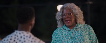 Movie still from “Tyler Perry's A Madea Homecoming” (2022), directed by Tyler Perry – A woman in a green shirt and a white necklace; Close Up shot, Over the shoulder angle