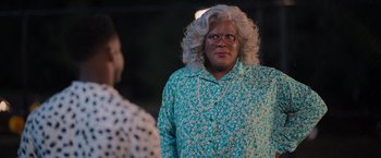 Movie still from “Tyler Perry's A Madea Homecoming” (2022), directed by Tyler Perry – A woman in a blue shirt and a white wig; Medium shot, Over the shoulder angle
