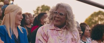 Movie still from “Tyler Perry's A Madea Homecoming” (2022), directed by Tyler Perry – A person wearing glasses and a pink shirt; Close Up shot, Over the shoulder angle
