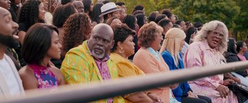 Movie still from “Tyler Perry's A Madea Homecoming” (2022), directed by Tyler Perry – A group of people sitting in a crowd of people; Medium shot, Over the shoulder angle