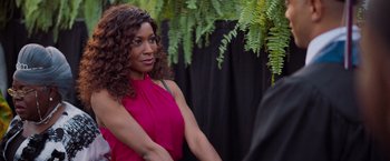 Movie still from “Tyler Perry's A Madea Homecoming” (2022), directed by Tyler Perry – A woman in a pink top standing in front of a plant; Close Up shot, Over the shoulder angle