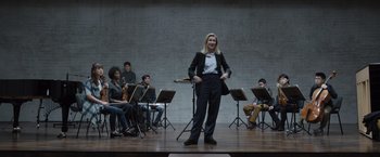 Movie still from “Tár” (2022), directed by Todd Field – A woman standing in front of a group of people on a stage; Wide shot, Low angle